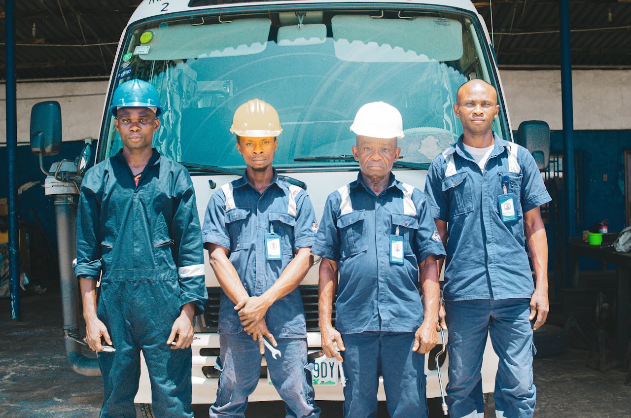 Group of mechanics in uniforms and hard hats in an automotive garage in Nigeria.