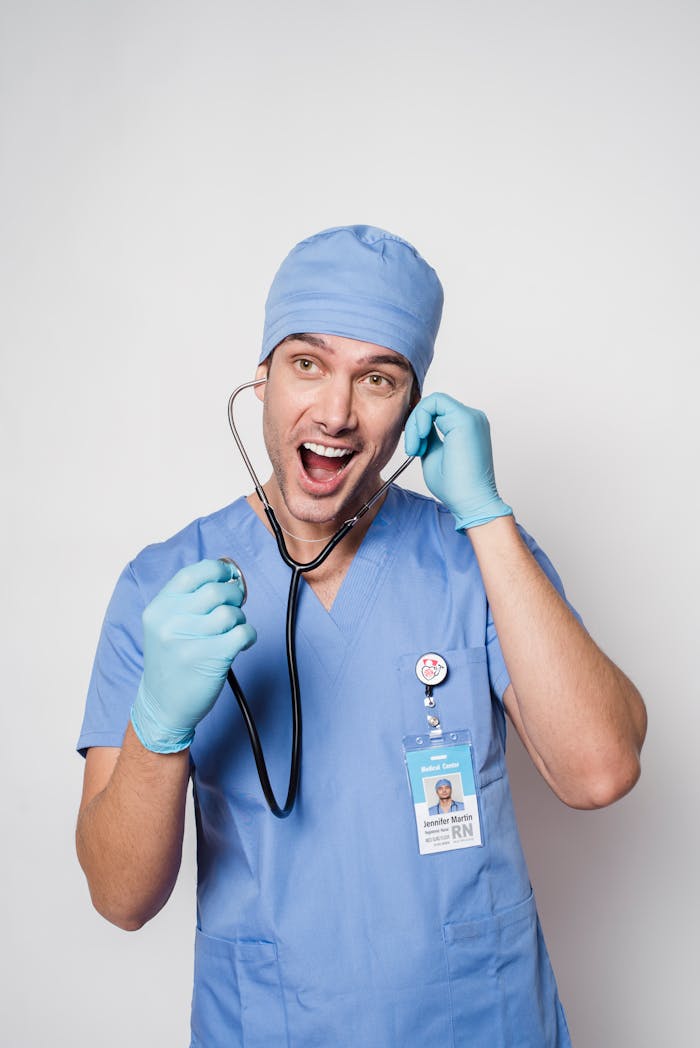 Amazed male medic in uniform and gloves with name tag putting stethoscope in ear and looking away with mouth opened